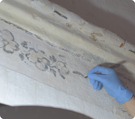 Fotografia de una pintura mural en proceso de restauración.